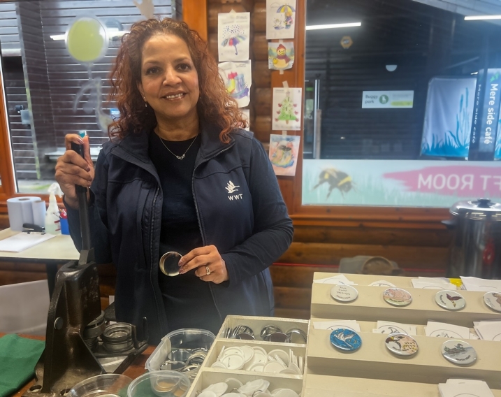 A volunteer holding onto the badge machine in the family craft room, at WWT Martin Mere